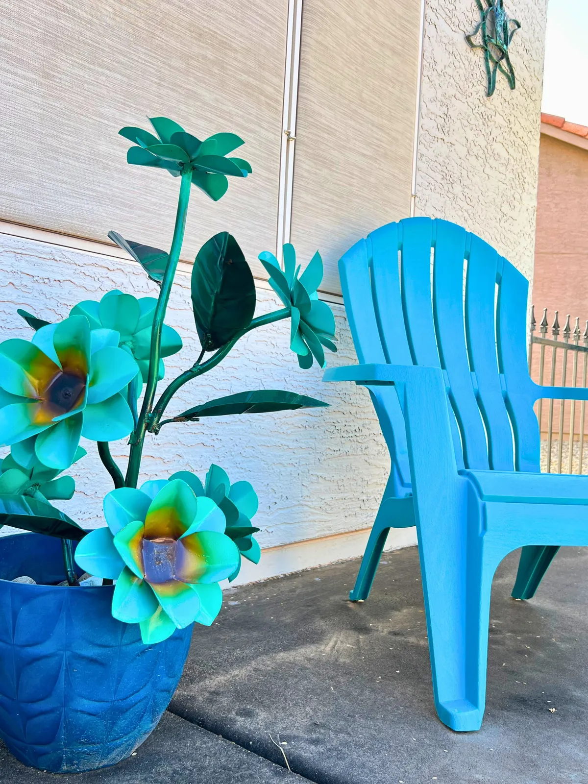 A cheerful outdoor nook featuring a turquoise chair, decorative flower plant, and a textured wall. The space exudes vibrancy and is ideal for casual chats or relaxing with neighbors, embodying the lively, friendly vibe of the community.