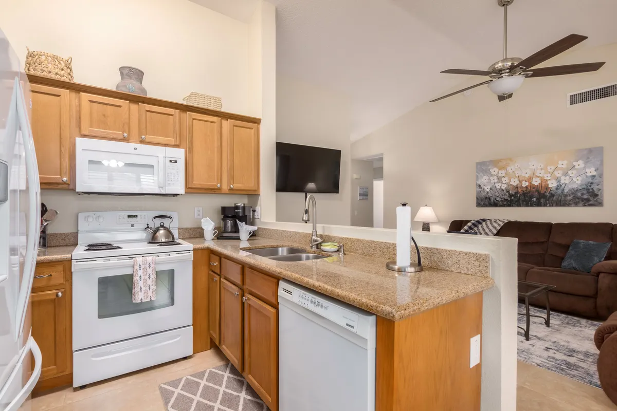 A well-lit kitchen with a central island, modern appliances, and a seamless view into the adjacent living area. The space is set up for cooking, entertaining, and social interaction, emphasizing the open-concept flow.